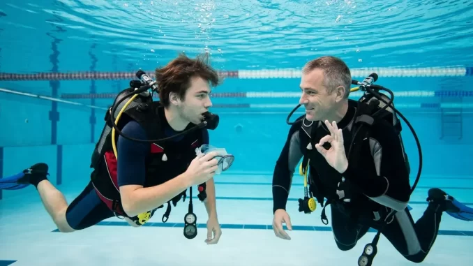 Tauchanfänger übt Angst vor Maskenabnahme mit einem ruhig begleitenden Tauchlehrer im Schwimmbad.