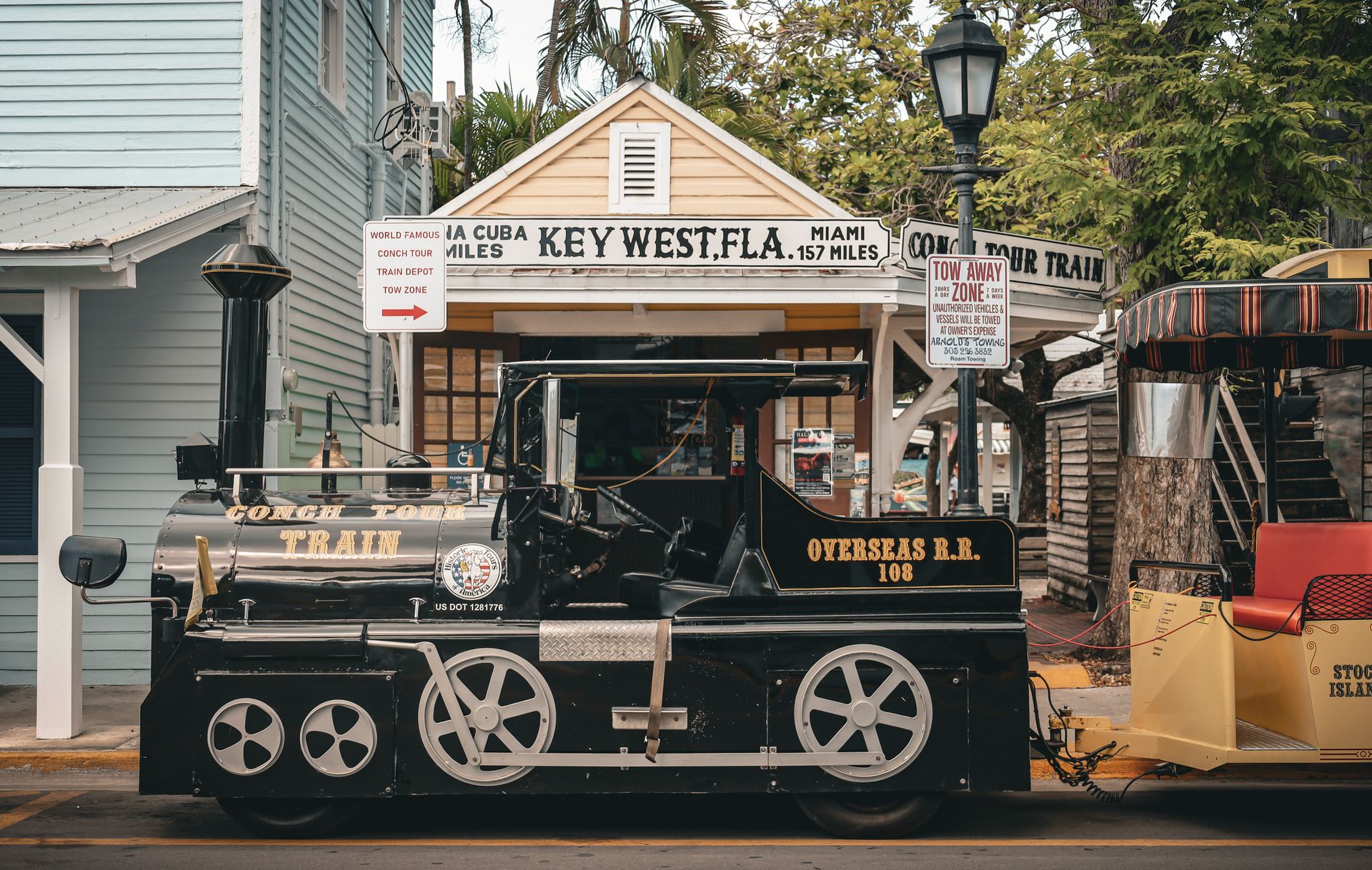 Conch Tour Train vor dem Depot in Key West, daneben ein Schild mit der Aufschrift Key West, Fla.