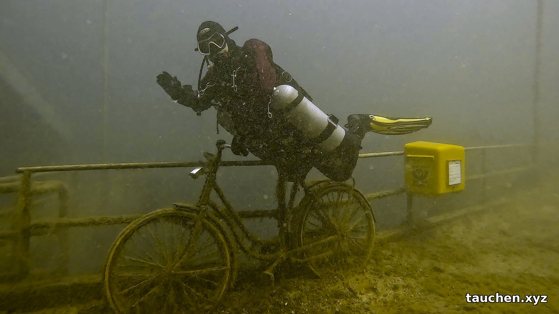 Versenktes Fahrrad neben gelbem Kasten am Geländer im Kreidesee Hemmoor