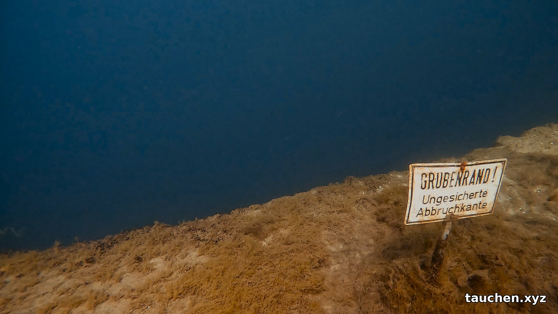 Warnschild Grubenrand ungesicherte Abbruchkante unter Wasser im Kreidesee Hemmoor