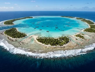 Luftaufnahme eines Atolls mit geschlossenem Riffring, Sandinseln, tuerkiser Lagune, Brandungslinie und einem Kanal zum offenen Meer