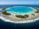 Luftaufnahme eines Atolls mit geschlossenem Riffring, Sandinseln, tuerkiser Lagune, Brandungslinie und einem Kanal zum offenen Meer