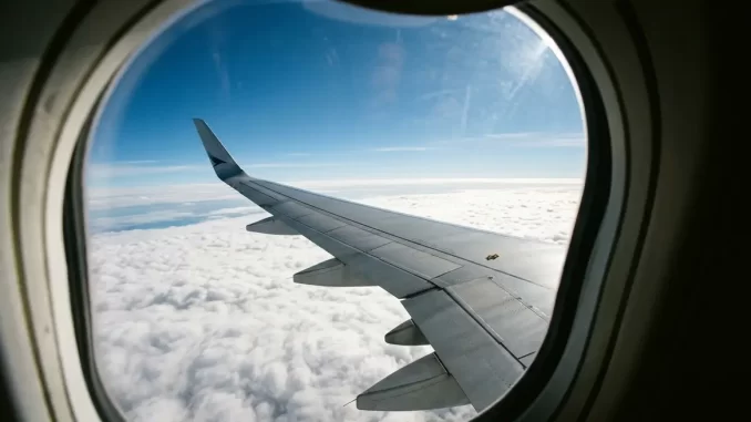 Blick aus dem Fenster eines Verkehrsflugzeugs über die Tragfläche auf eine geschlossene Wolkendecke