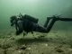 Taucher bewegt sich im Frogkick waagerecht dicht über einem sandigen Seegrund, ohne Sediment aufzuwirbeln.