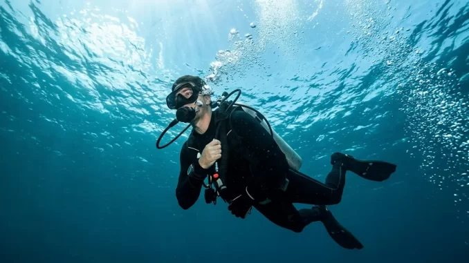 Ein Taucher schwimmt mit dem Automaten im Mund unter gleichmäßigem Ausatmen zur Wasseroberfläche.