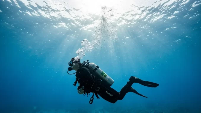 Taucher steigt kontrolliert auf und atmet aus, eine Kette feiner Blasen zieht zur Wasseroberfläche