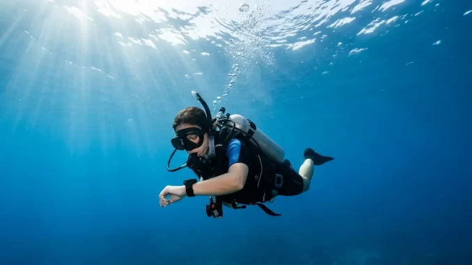 Taucher schwebt kurz unter der Wasseroberfläche und blickt auf sein Handgelenk.
