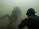 Taucher im truben Baggersee, der Tauchpartner ist in wenigen Metern Entfernung nur noch als Silhouette erkennbar.