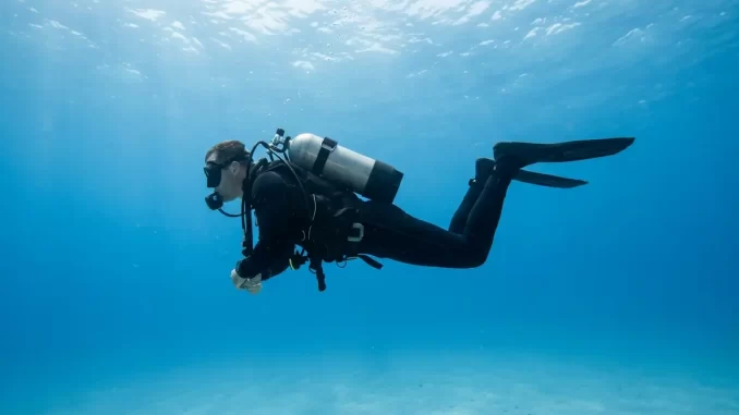 Gerätetaucher in waagerechter Wasserlage im Mittelwasser, Schultern und Knie auf einer Ebene, Flossen flach.
