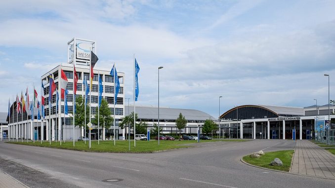Gelände der Messe Friedrichshafen mit Fahnenmasten, Verwaltungsgebäude und Hallen