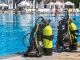 Zwei Tauchgerätesätze mit gelben Flaschen stehen am Beckenrand eines Freibads – typischer Aufbau für eine Tauchausbildung im Pool