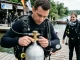 Taucher prüft Ventil, Manometer und Kennzeichnung einer Tauchflasche vor dem Tauchgang.
