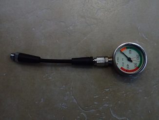 Analoges Finimeter mit bar-Skala und farbig hervorgehobenem Reservebereich, an einem kurzen Hochdruckschlauch mit Anschlussverschraubung.