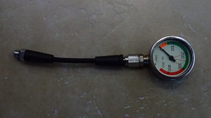 Analoges Finimeter mit bar-Skala und farbig hervorgehobenem Reservebereich, an einem kurzen Hochdruckschlauch mit Anschlussverschraubung.