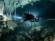 Taucher durchstoesst in einer gefluteten Hoehle die Halokline; unterhalb der Schichtgrenze erscheint das Wasser schlierig verzerrt.