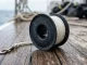 Schwarzer Fingerspool mit dicht aufgewickelter weisser Leine und durchgehendem Mittelloch liegt auf dem Holzdeck eines Tauchbootes.