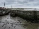 Kaimauer bei Niedrigwasser mit deutlich sichtbarer Bewuchslinie des Hochwassers und zwei trockengefallenen Booten im Schlick.