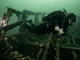 Feine Angelschnur hat sich an einem Wrack um Flosse und Knöchel eines ruhig liegenden Tauchers gelegt.